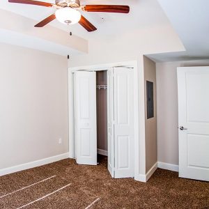 Empty bedroom with rug, ceiling fan, and spacious closet