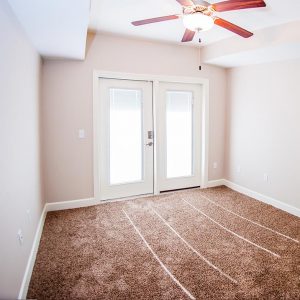 Empty bedroom. features rug, ceiling fan, and french-style doors to patio